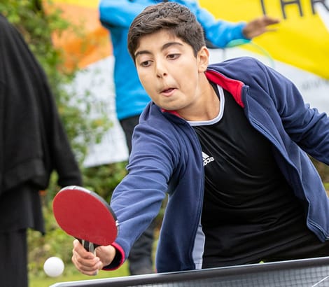 Photo of a boy playing table tennis outdoors